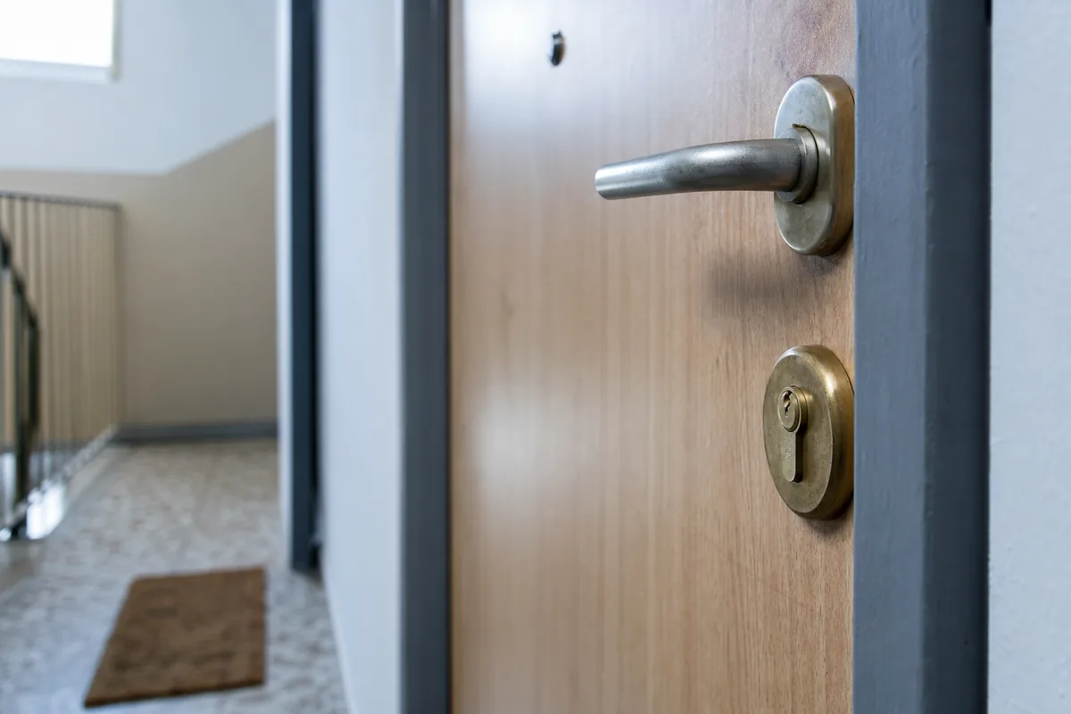 Porte palière d’immeuble avec son cylindre européen sur un palier de cage d’escalier