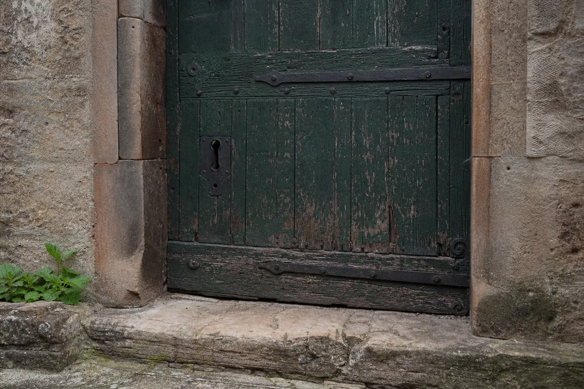 Porte ancienne en chêne d’une maison du centre de Milly-la-Forêt encadrée de pierre de grès