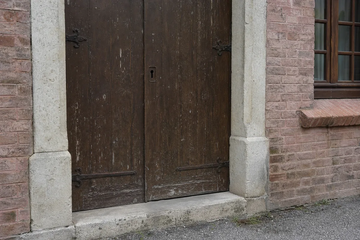 Façade de brique foraine d&rsquo;une maison ancienne de Montauban avec sa porte d&rsquo;entrée en bois à large huisserie