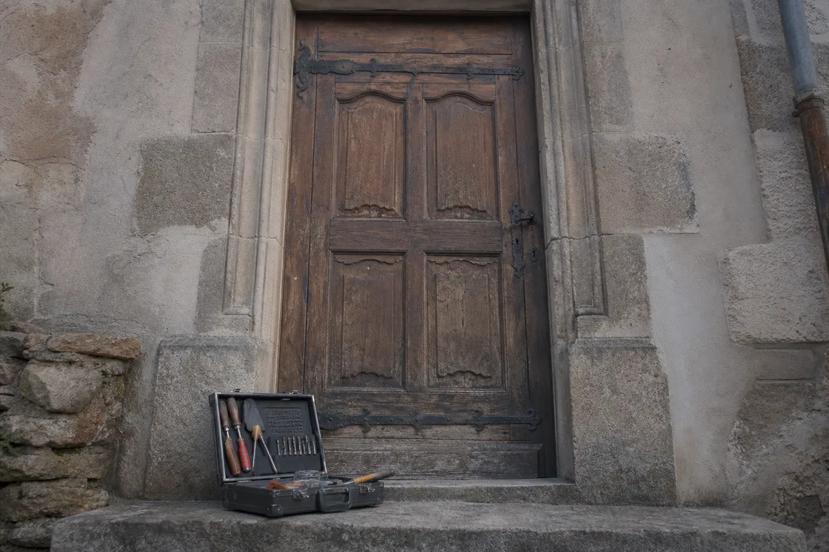 Porte d&rsquo;entrée en chêne d&rsquo;une maison de centre ancien, façade en pierre en fin de journée